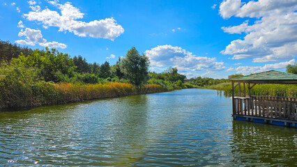 Wooden pier extending into serene lake reflecting blue sky and clouds