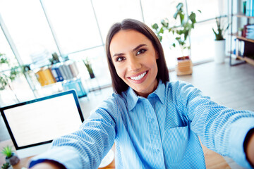 Young Professional Woman Smiling and Taking a Self Portrait in a Bright Modern Workspace