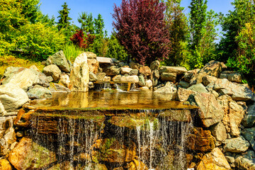 Slowly flowing over a rocky base. Beautiful decorative stream in a city public park.