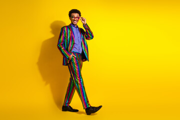 Young man in a stylish colorful striped suit smiling confidently against a vibrant yellow...
