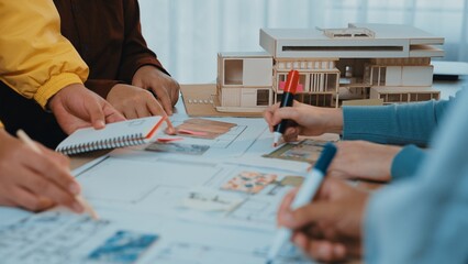 A group of architects and designers collaborates on an architectural project, sketching plans and discussing innovative ideas at a design studio workspace. SACTR