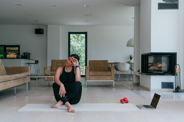 Obraz premium Woman Relaxing After Home Workout in a Modern Living Room