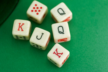 Six colorful dice displaying playing card values on a green tabl