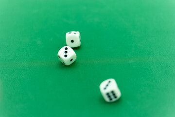 Three white dice resting on a green felt gaming table after bein