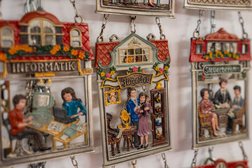 Handcrafted miniature wall hangings show a jeweler and informatics shop, with small figures,...