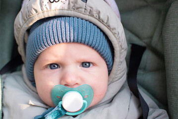 Portrait of a baby boy with a pacifier, in warm clothes.