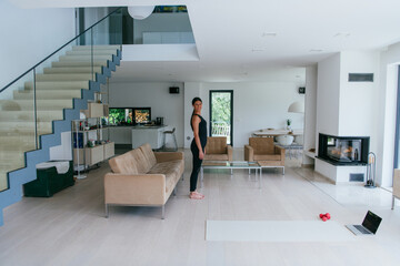 Young Beautiful Female Exercising, Stretching and Practising Yoga with Trainer via Video Call Conference in Bright Sunny House. Healthy Lifestyle, Wellbeing and Mindfulness Concept