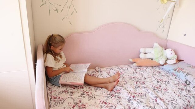 A little girl is reading a book in her room at home