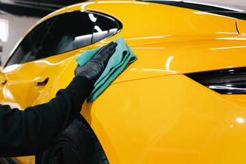 Microfiber hand cleaning and washing sports car using microfiber towel in garage. Manual washing...