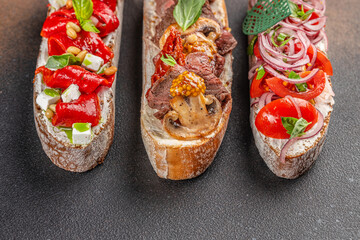 Assorted bruschetta with various toppings. Appetizers with Italian antipasti snacks on a dark background. top view. copy space for text