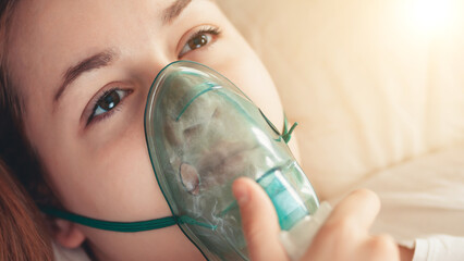 Young woman struggling with virus and asthma using oxygen mask outdoors