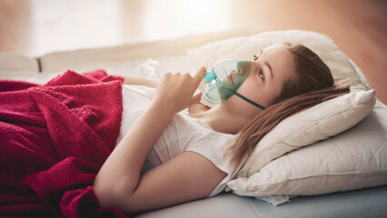 Young woman struggling with virus and asthma using oxygen mask outdoors
