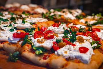 Freshly baked pizza with golden crust, cherry tomatoes, creamy cheese, greens, and olives, reflecting Italian culinary traditions in Bergamo, Italy.