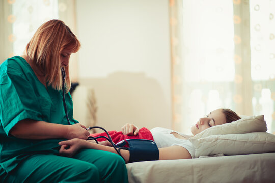 Doctor helping young woman with respiratory problems at home - Powered by Adobe