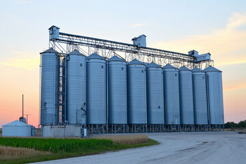 Obraz premium Grain elevators silhouetted against a colorful sunset Generative AI