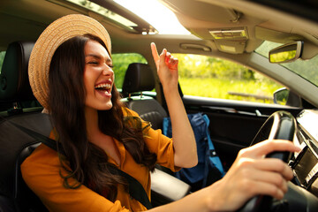 Joyful lady enjoying listening to music while driving car and singing songs, woman ready for trip,...