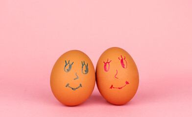 Closeup of two eggs with happy faces on a pink surface. Smilies on eggs