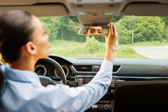 Happy lady adjusting the rearview mirror while sitting on driver's seat of new car, enjoying automobile and test drive