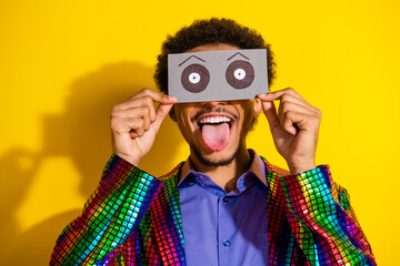 Energetic young man with funky outfit posing playfully against a vibrant yellow background,...