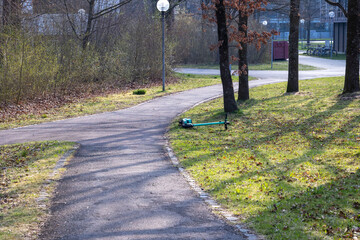 Abandoned e-scooter lying on the grass beside a pathway, University of Augsburg campus, Germany,...