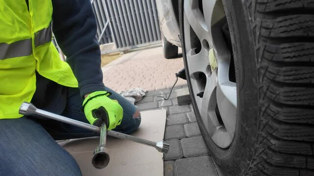 A guy changes tire on street to summer tire in nature