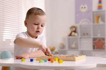 Motor skills development. Little boy playing with Times table tray indoors