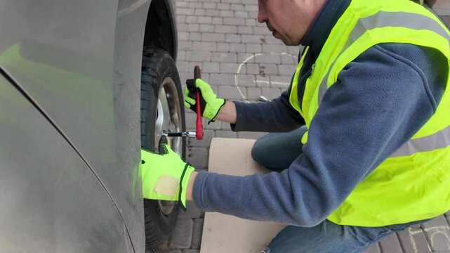 A guy changes tire on street to summer tire in nature