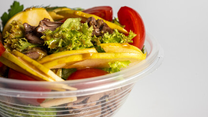 summer salad, tomato salad, vegetables, in a plastic container on a light background, food delivery, takeaway food