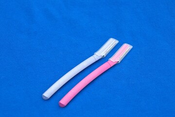 facial dermaplaning razors against blue backdrop