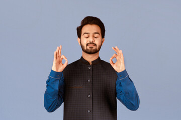 Peaceful Indian man meditating and making yoga mudras on lilac background
