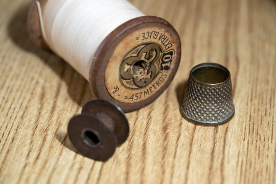 hilo, dedal y carrete vintage sobre mesa de madera