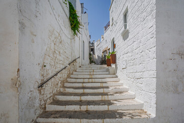 Scenic view of Ostuni, Italy's 'White City,' showcasing whitewashed buildings under a clear blue sky, with narrow streets and historic architecture illuminated by sunlight.