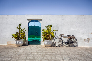 Scenic view of Ostuni, Italy's 'White City,' showcasing whitewashed buildings under a clear blue sky, with narrow streets and historic architecture illuminated by sunlight.