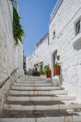 Scenic view of Ostuni, Italy's 'White City,' showcasing whitewashed buildings under a clear blue sky, with narrow streets and historic architecture illuminated by sunlight.