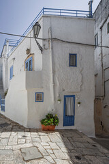 Scenic view of Ostuni, Italy's 'White City,' showcasing whitewashed buildings under a clear blue sky, with narrow streets and historic architecture illuminated by sunlight.