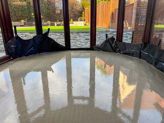 Newly laid wet concrete on the floor of a conservatory of a house. No people.