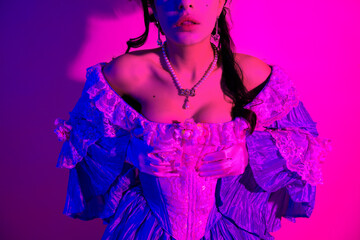 Elegant woman in a vintage-inspired corset dress illuminated by vibrant pink and purple neon light