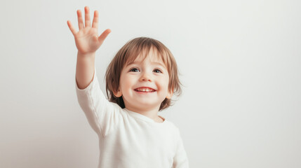 A small smiling child with a raised hand on a white background