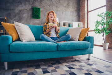 Obraz premium Full size photo of young blonde woman excited watch tv eat popcorn dressed yellow plaid outfit cozy day light home interior living room