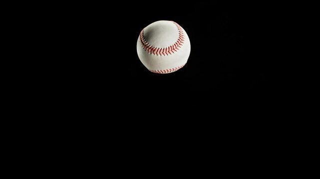 Rotating and Flying White Baseball Ball on Black Background . Filmed on High Speed Cinematic Camera at 1000 fps