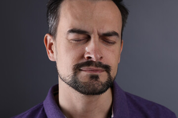Sad man crying on grey background, closeup