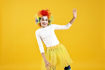 Happy girl dressed like clown on yellow background. Surprise party