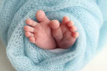 Baby foot on blue soft coverlet, blanket. Close-up of tiny, cute, bare toes, heels and feet of a newborn girl, boy. 