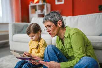 grandmother and grandchild spend time together and read a book at home
