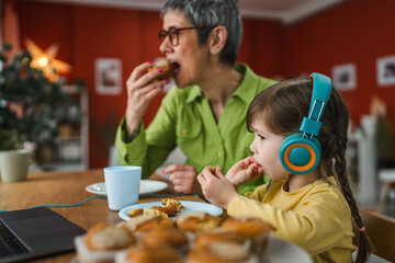 cute little girl enjoy while watch cartoon on laptop with her grandma