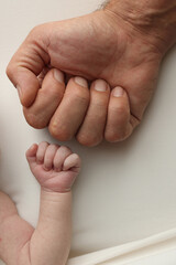 Two hands: man and child. Father and son touching fists. Dad and newborn son boys holding hands...
