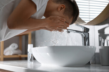 Man washing his face over sink in bathroom