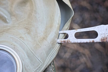 one metal blade of an old knife cuts through a gray rubber gas mask