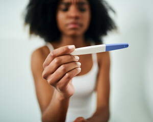 Hands, worry and black woman with negative pregnancy test in bathroom, apartment or house. Upset,...