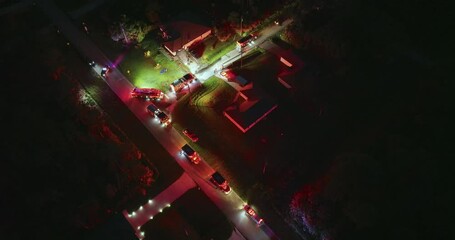 First responders investigating carbon monoxide gas hazard at residential home in Florida, USA. Firefighter trucks with bright flashing blinker lights at night.